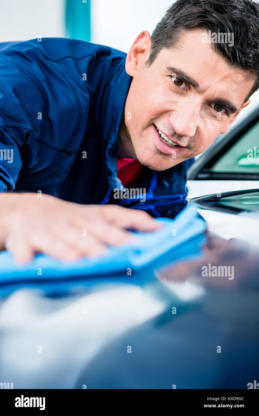 Mann mit einem saugfähigen Tuch für die Trocknung der Oberfläche eines Auto Stockfoto