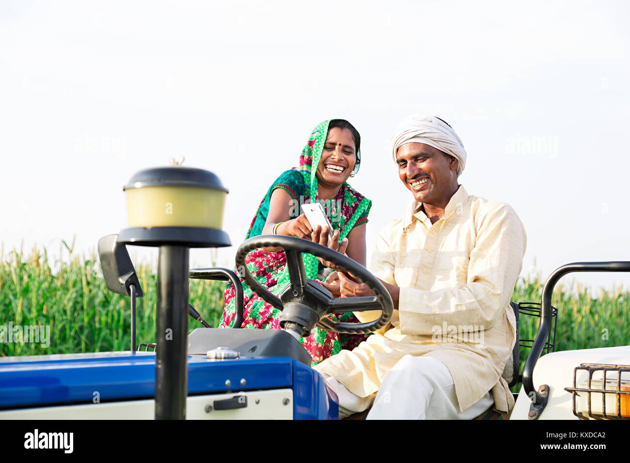 2 ländlichen Bauern Paar Traktor Messaging Telefon lächeln Feld Stockfoto