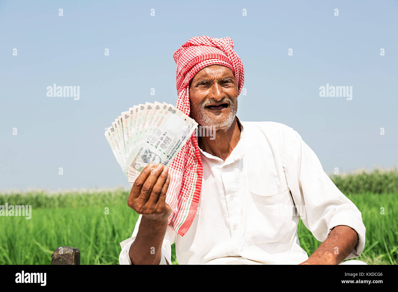 Indischen ländlichen Bauern alter Mann zeigt Rupees Notes Feld Sitzen Stockfoto