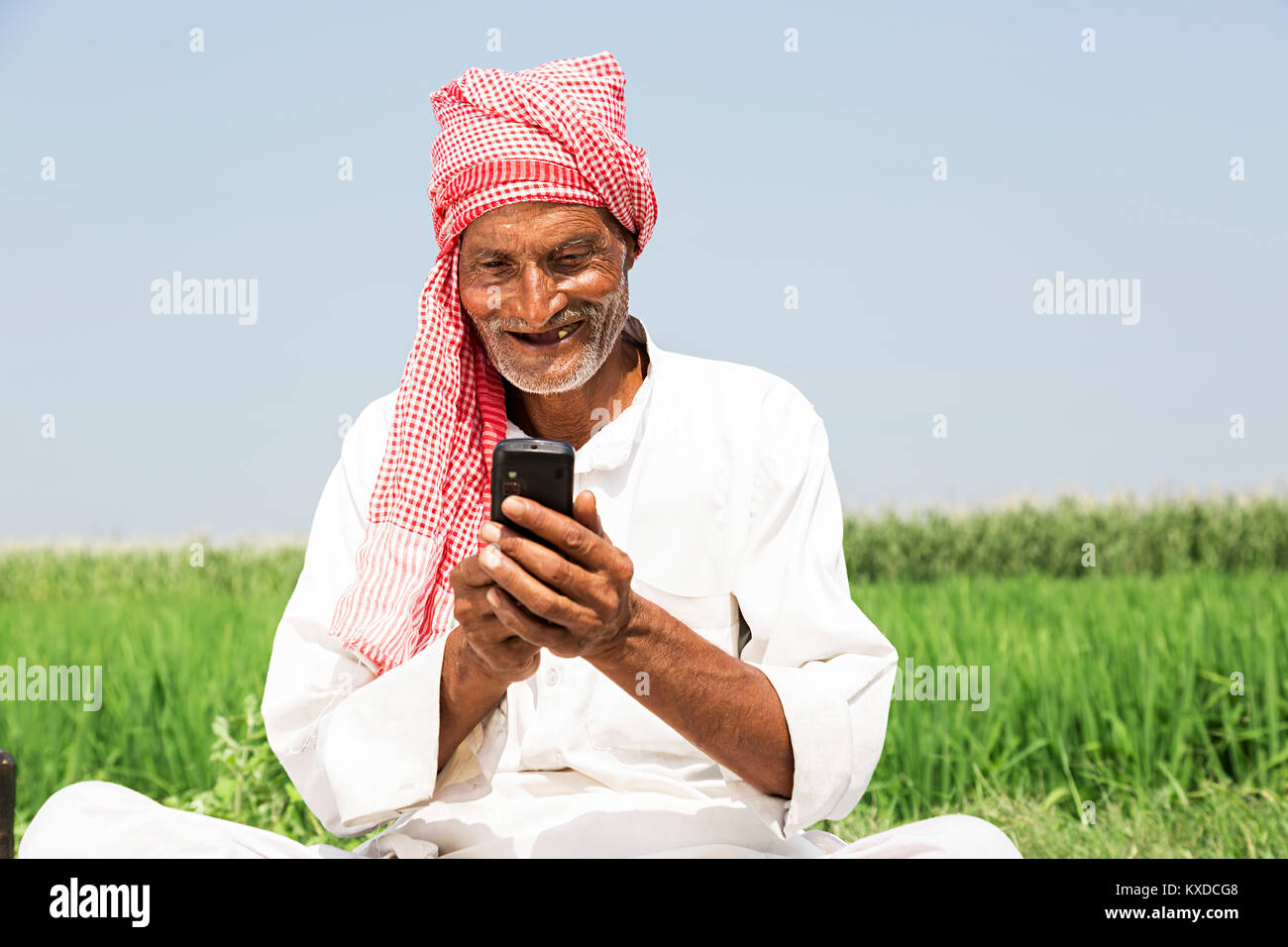 1 Indischen ländlichen Bauern alter Mann Telefon sitzen Farm Stockfoto