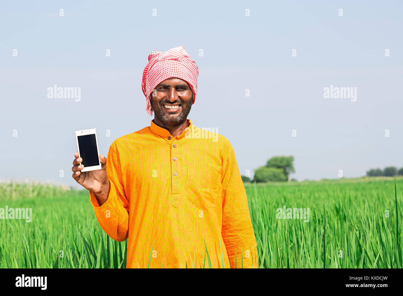 Indischen ländlichen Bauern Mann Feld mit Smart Phone lächelnd Stockfoto
