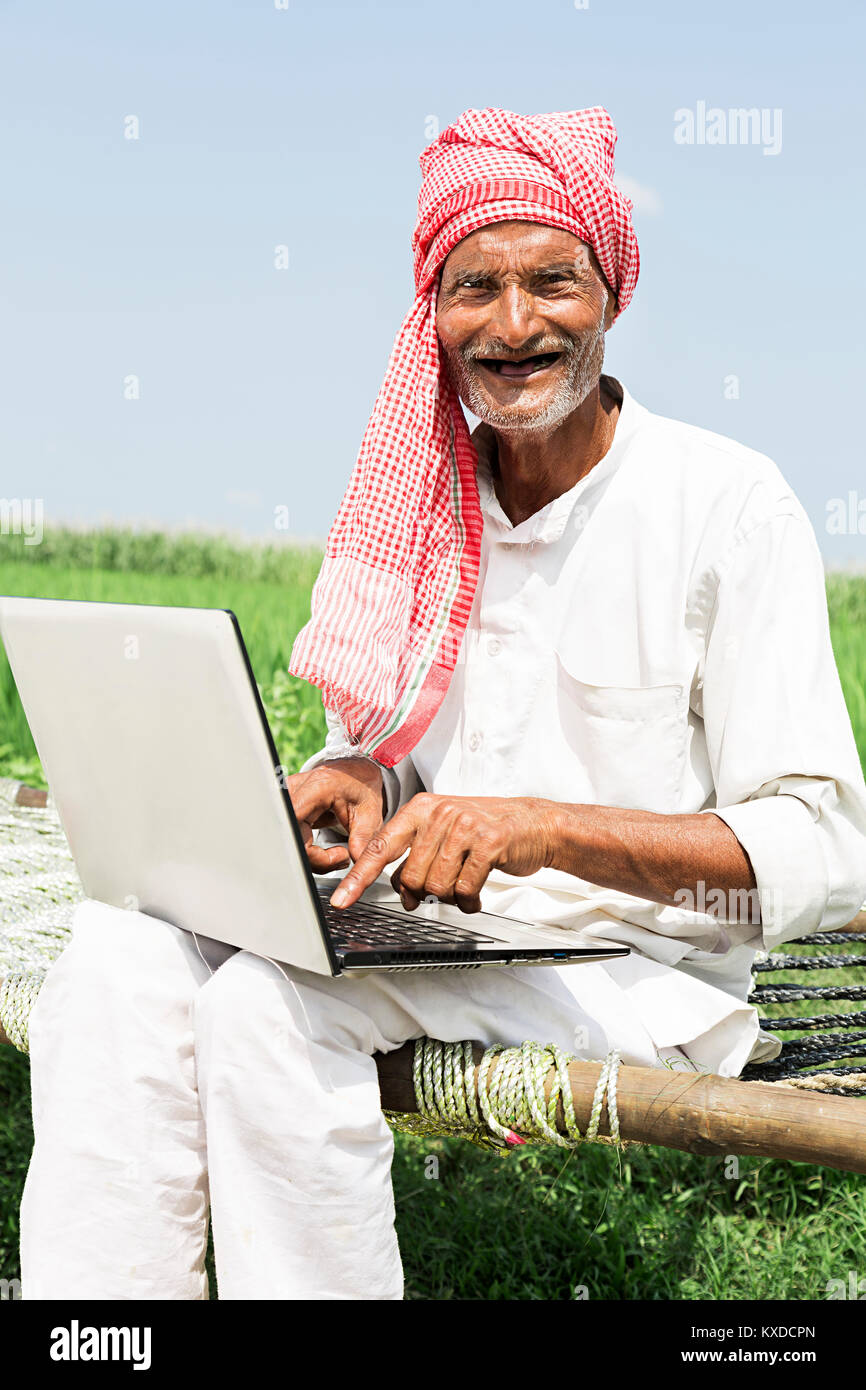 1 Indischen älterer Mann sitzt Charpai Feld Laptop arbeiten Lächeln Stockfoto