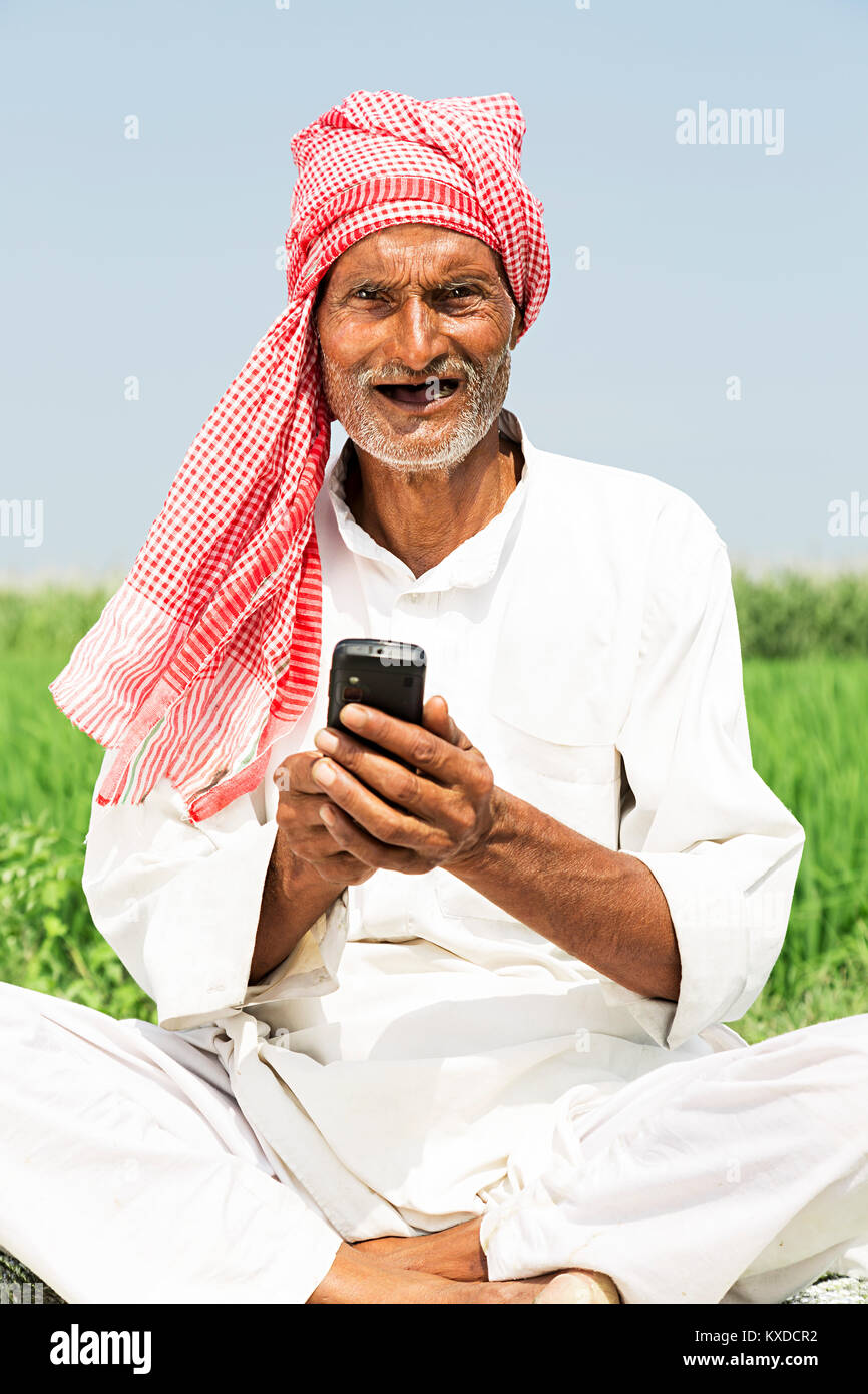 1 indischen Bauern älterer Mann sitzt Farm senden Messaging Telefon Stockfoto