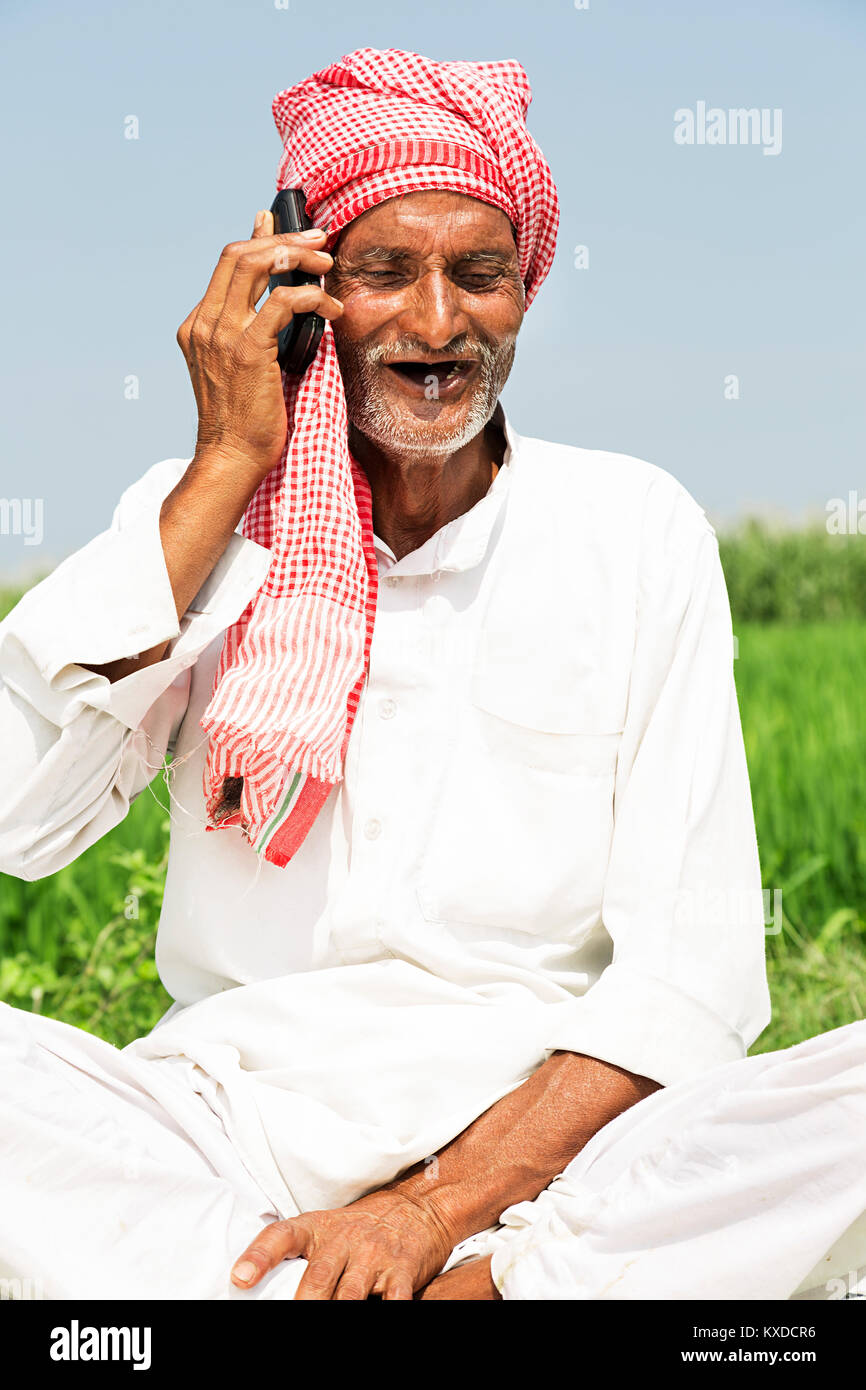 1 Indischen ländlichen Bauern alten Mann Telefon sitzen, Feld Stockfoto