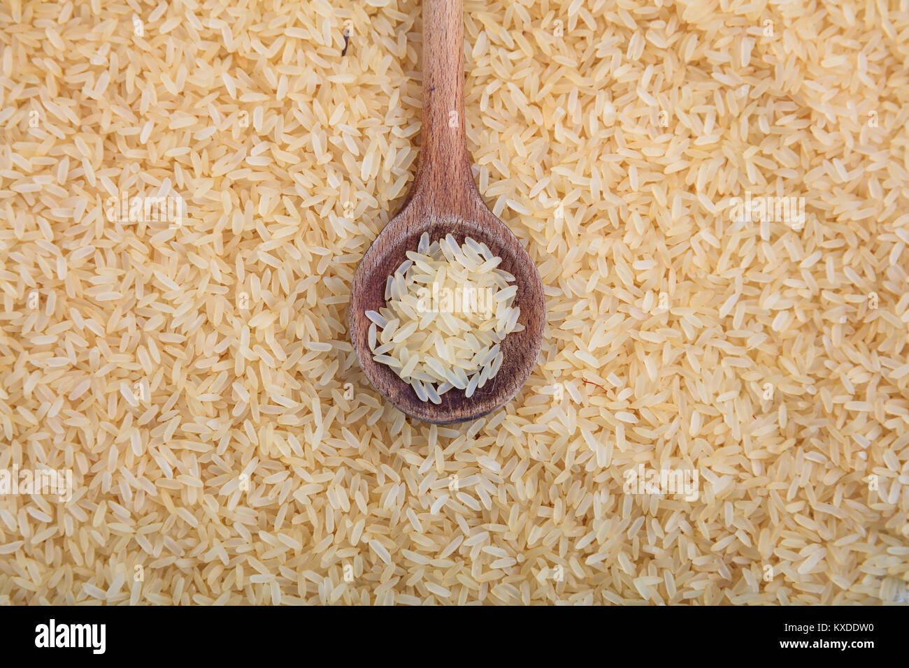 Holzlöffel auf parboiled Reis Hintergrund Stockfoto