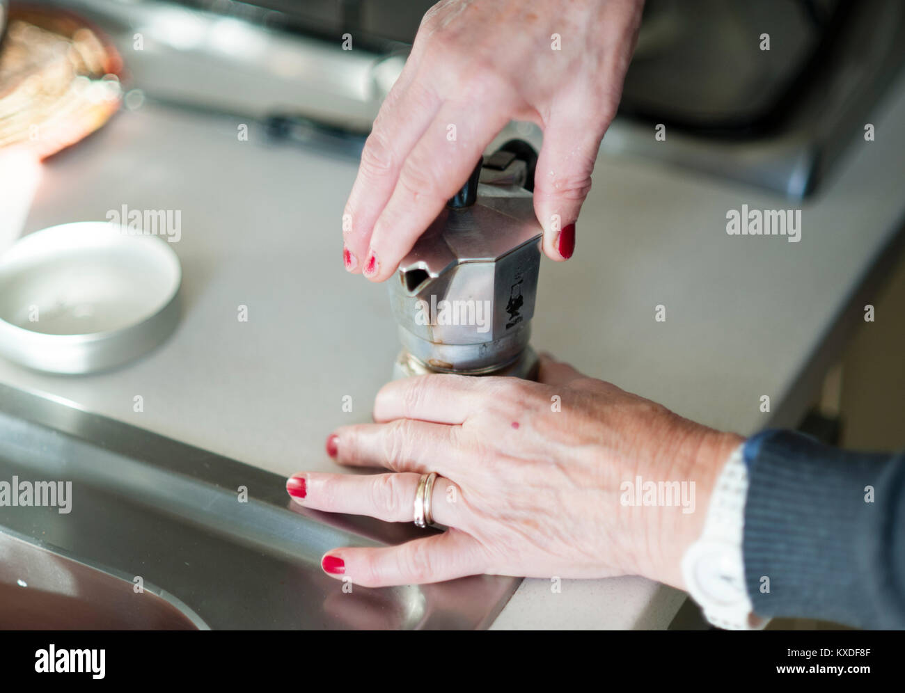 Eine ältere Frau bereitet einen Espresso mit einem traditionellen Bialetti Espressomaschine Stockfoto