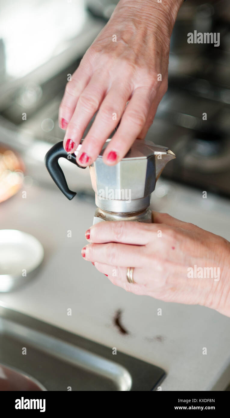 Eine ältere Frau bereitet einen Espresso mit einem traditionellen Bialetti Espressomaschine Stockfoto