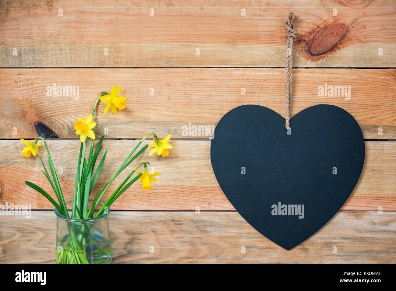 Holzbohlen mit Narzissen und eine Tafel in der Form eines Herzens, liebe Grußkarte Hintergrund mit Platz für Text kopieren Stockfoto