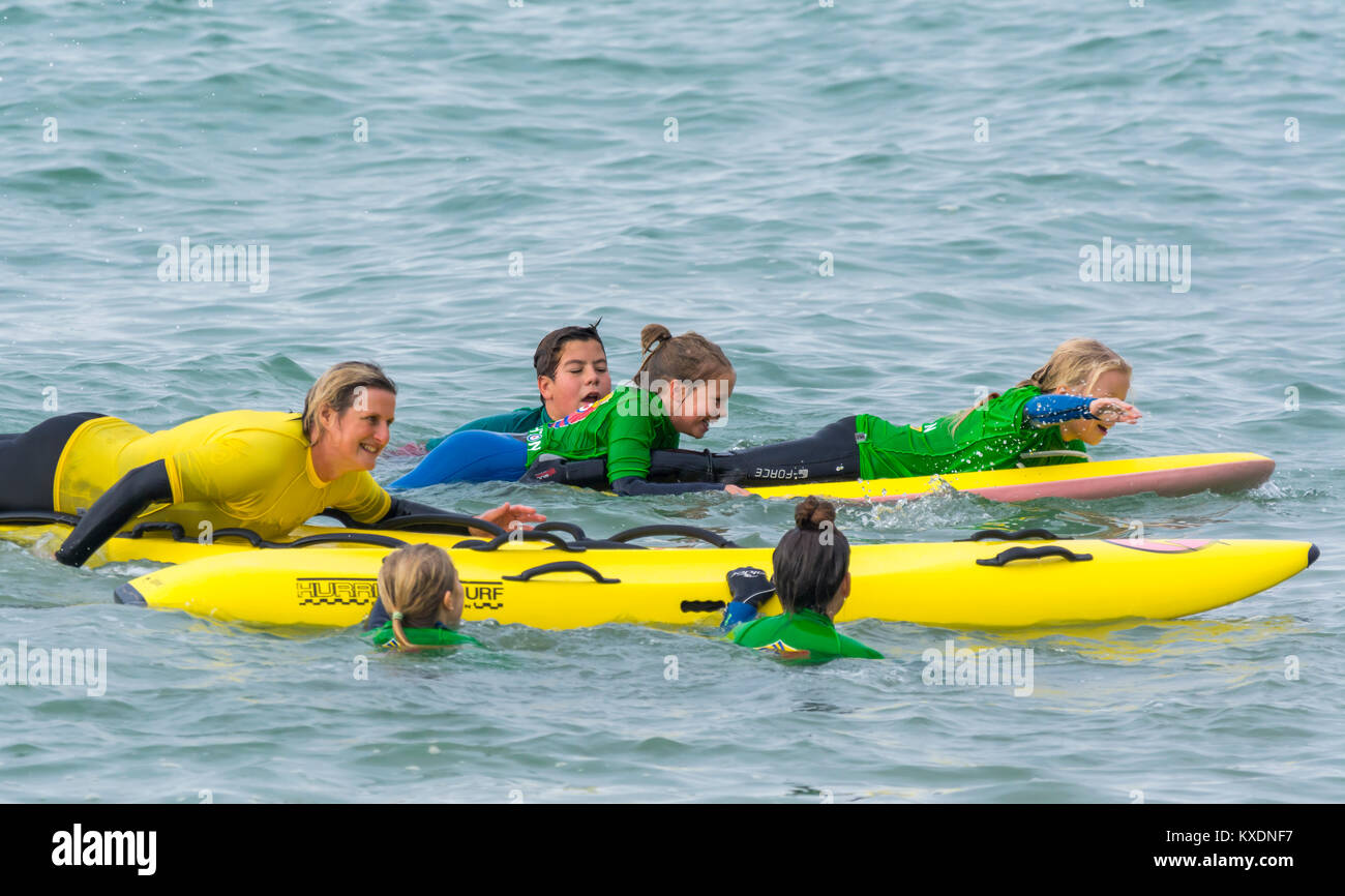Frau Ausbildung junger Kinder, wie ein paddleboard im Meer in der UK zu verwenden. Stockfoto