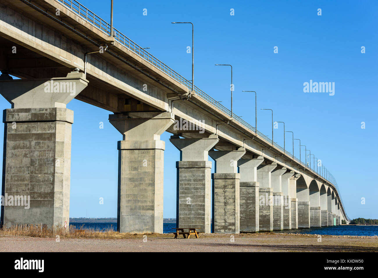 Leere Bank unter Betonbrücke. Graue Säulen tragen das Gewicht der Struktur. Wesentlicher Bestandteil der Infrastruktur und der Insel Öland an Main link Stockfoto