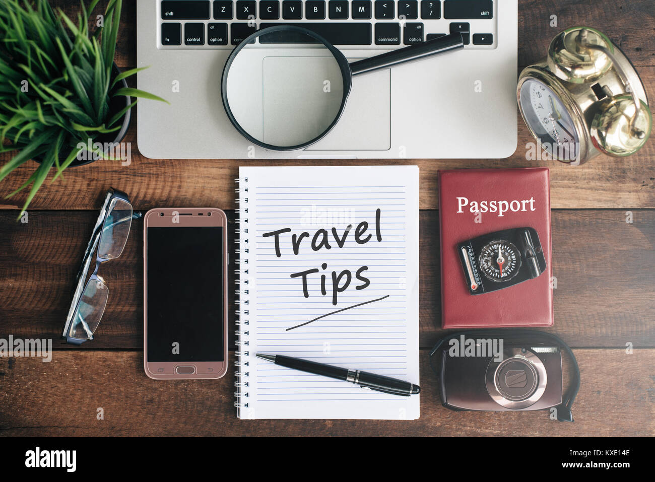 Laptop, Notebook, Smartphone, Reisepass, Kompass, Lupe und Uhr mit REISETIPPS Wort auf Holztisch. travel Concept Stockfoto