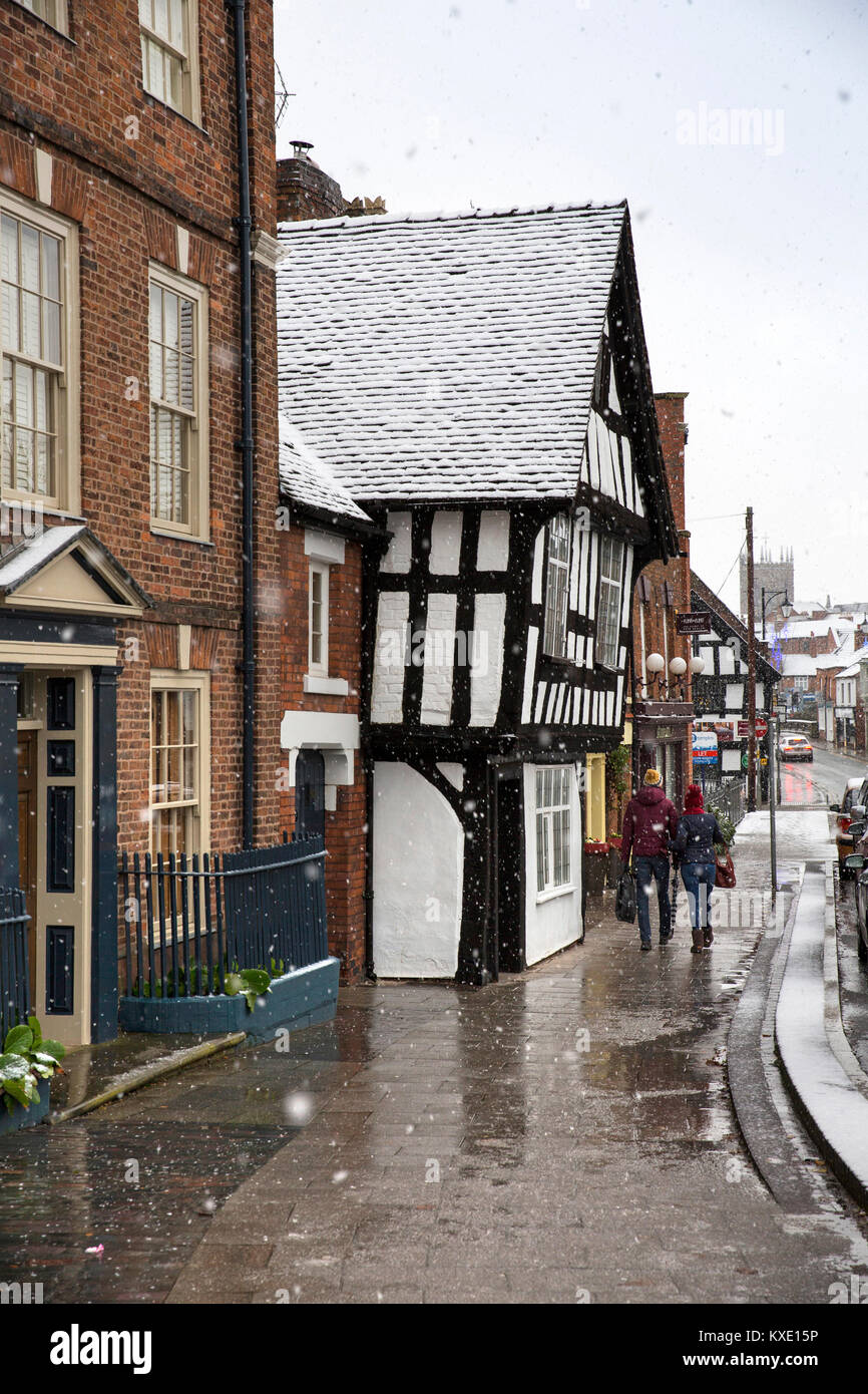 Großbritannien, England, Cheshire, Nantwich, Welsh Zeile, Paar wandern vorbei an alten Fachwerkhaus im Winter schnee Stockfoto