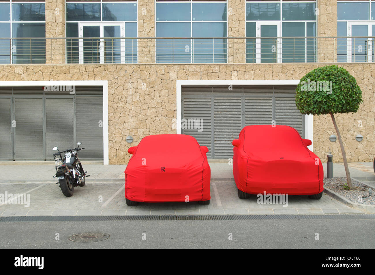 Rolls Royce mit einem roten Abdeckung vor Staub und Schmutz geparkt Neben einem Motorrad, Zypern Stockfoto