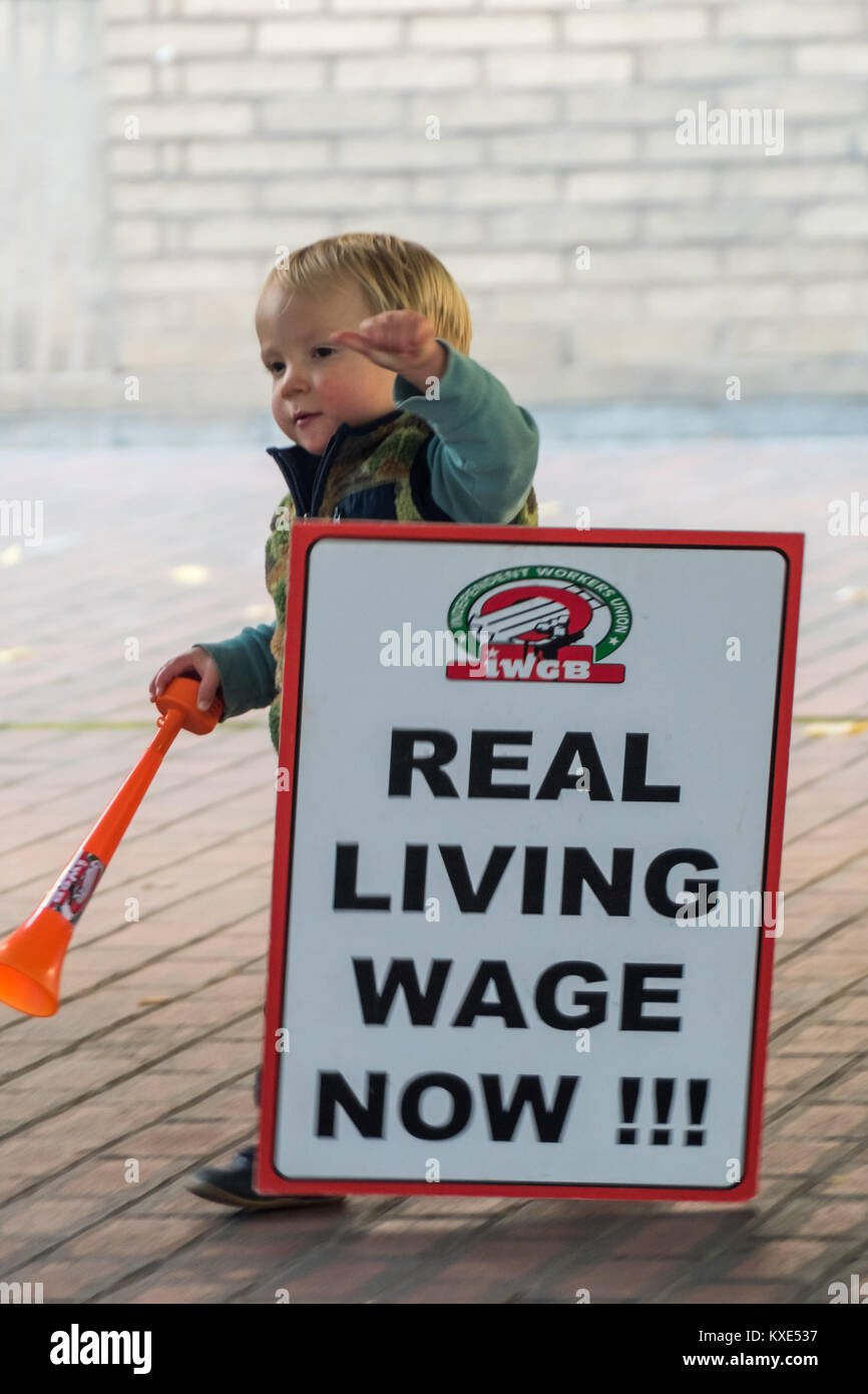 IWGB Eine junge Demonstrantin, die auf dem Vorplatz des Southwark Crown Court verirrt hat, macht den Fehler, fallen seine Plakat Aufruf zum "wirklichen Lohn Jetzt!!!" Stockfoto