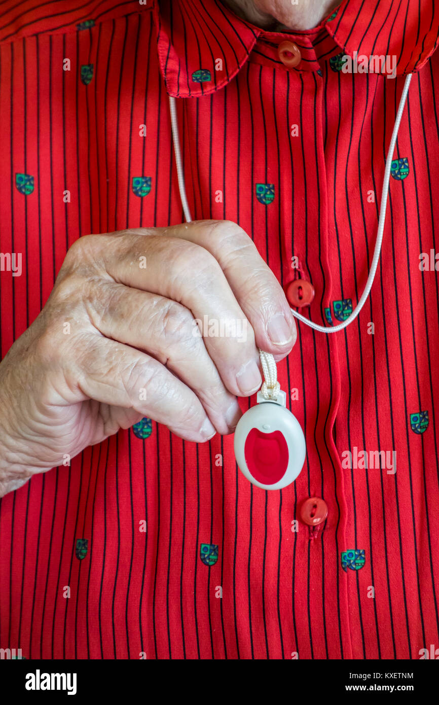 Nahaufnahme einer Hand, die Lebensrettenden personal Alarm für ältere und behinderte Menschen übersicht Anhänger mit Druckknopf Stockfoto