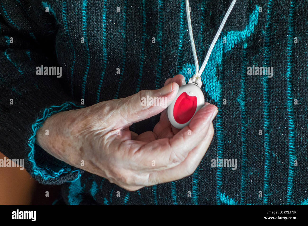 Nahaufnahme einer Hand, die Lebensrettenden personal Alarm für ältere und behinderte Menschen übersicht Anhänger mit Druckknopf Stockfoto