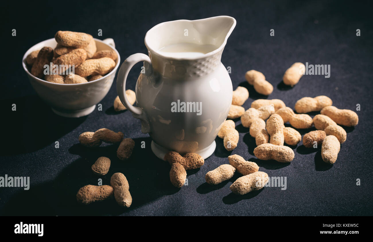 Vegan Milch aus Erdnüssen auf schwarzem Hintergrund Stockfoto