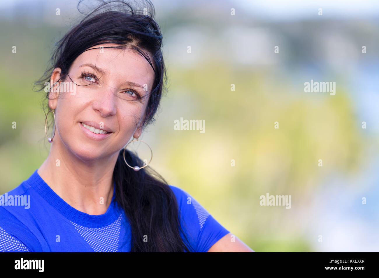 Junge osteuropäische Frau mit langem Haar in einem Zopf stehen draußen auf der Suche oben auf der Seite mit einem nachdenklichen kontemplativen Ausdruck wit Stockfoto