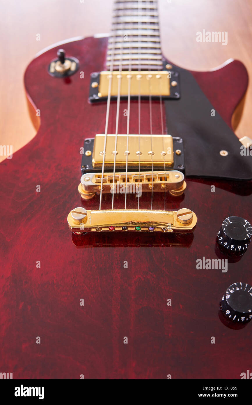 Glänzend Weinrot Gitarre mit goldene Hardware auf einem Holztisch mit Fokus auf den Stop Bar Stockfoto Glänzend Weinrot Gitarre mit goldene Hardware auf einem Holztisch mit Fokus auf den Stop Bar Stockfoto