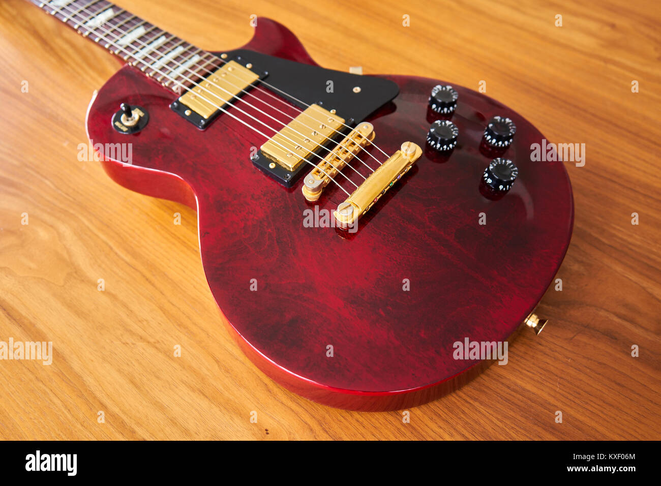 Glänzend Weinrot Gitarre mit goldene Hardware auf einem Holztisch, Seitenansicht Stockfoto