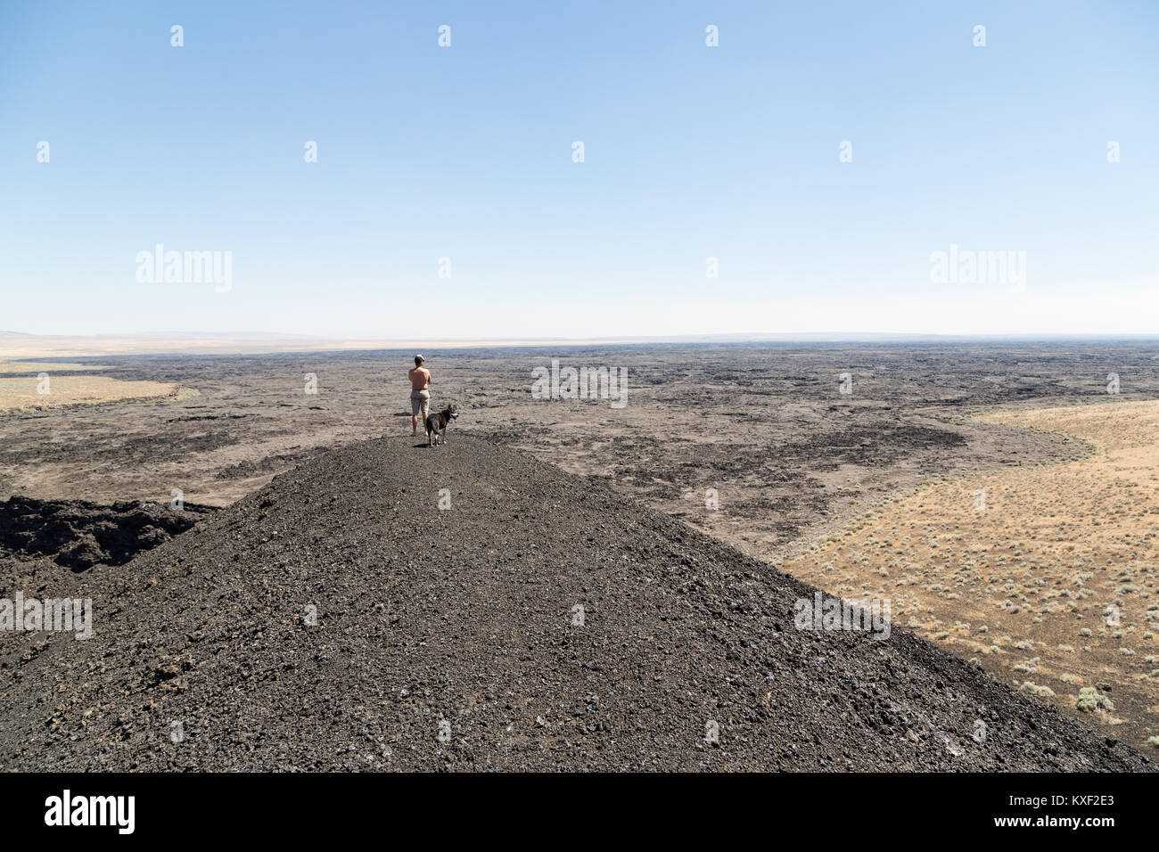 Ein Mann steht an der Spitze einer Schlackenkegel bewundern, eine riesige Lavastrom in der Nähe der Jordan Krater, Oregon. Stockfoto