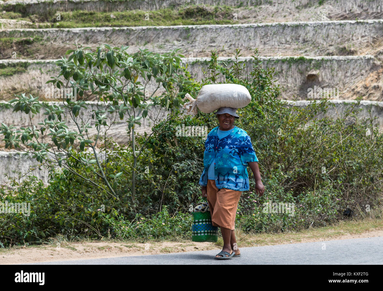 Eine lokale Frau mit einem großen Lächeln mit einem Sack über dem Kopf. Madagaskar, Afrika. Stockfoto