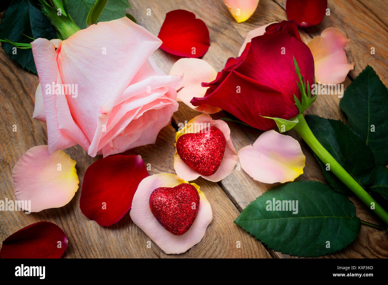 Valentines Tag Begrüßung mit rosa und roten Rosen und zwei Herzen auf der rustikalen Holzmöbeln Hintergrund, Hochzeit Einladung. Stockfoto