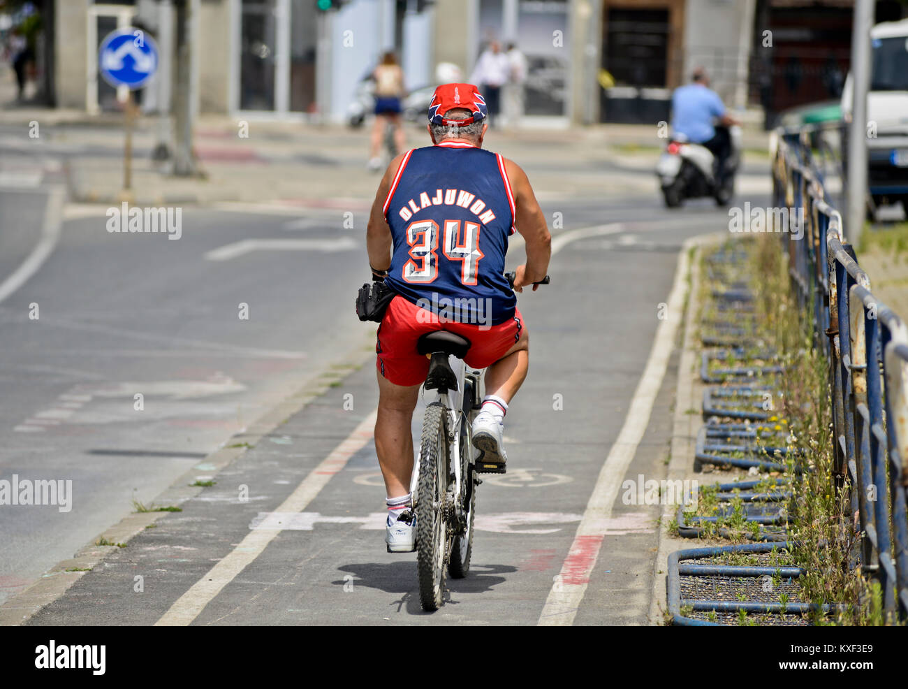 Ein Mann mit dem Fahrrad das Tragen eines Basketball Jersey (hakeem Olajuwon, Houston Rockets). Skopje, Mazedonien Stockfoto
