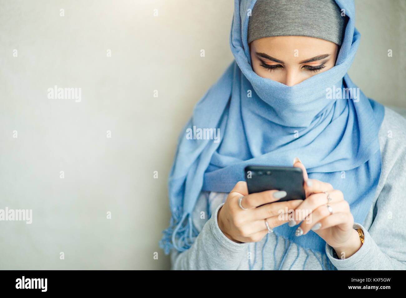 Muslimische junge Frau Verwendung von Smart Phone im Cafe Stockfoto