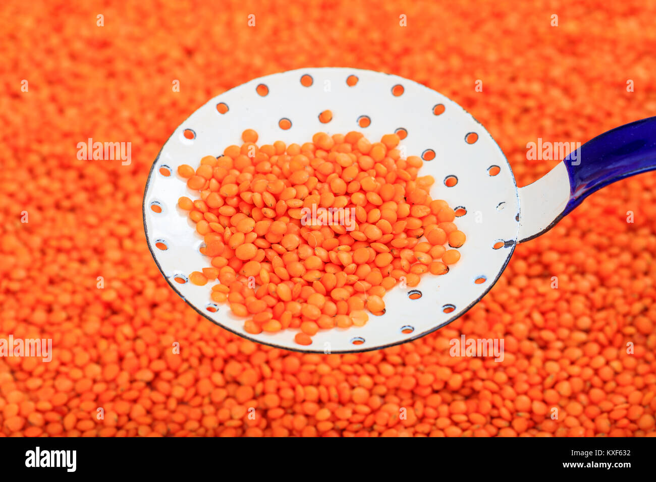 Metallische alte Löffel und orange Linsen Hintergrund Stockfoto