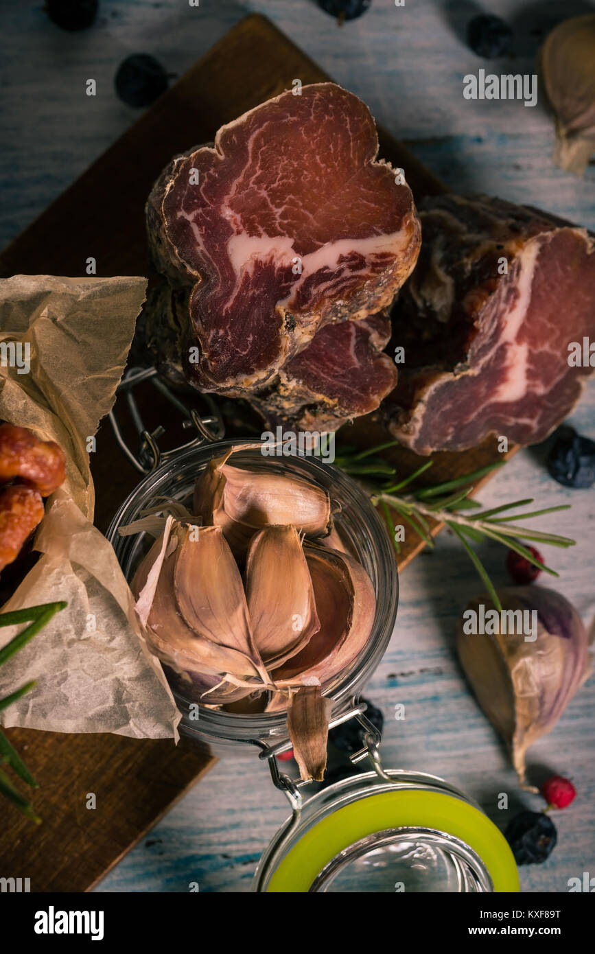 Vertikale Foto mit Top Aussicht auf gestapelten Getrocknete italienische Fleisch von Wildschweinen Schwein auf Blau und Weiß vintage Holzbrett mit Knoblauch, Farbe trocknen ber platziert Stockfoto