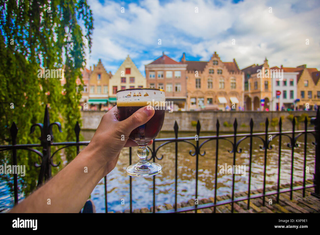 Glas Bier auf Brügge Stadtbild Hintergrund. Hand mit Bier Glas in Brügge, Belgien. Stockfoto