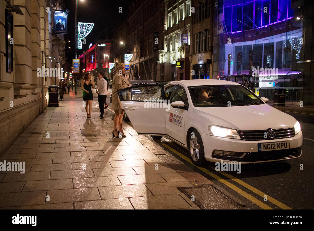 Frauen, die aus einem Taxi heraus an Silvester auf der Park Row im Zentrum der Stadt Leeds, England Großbritannien Stockfoto