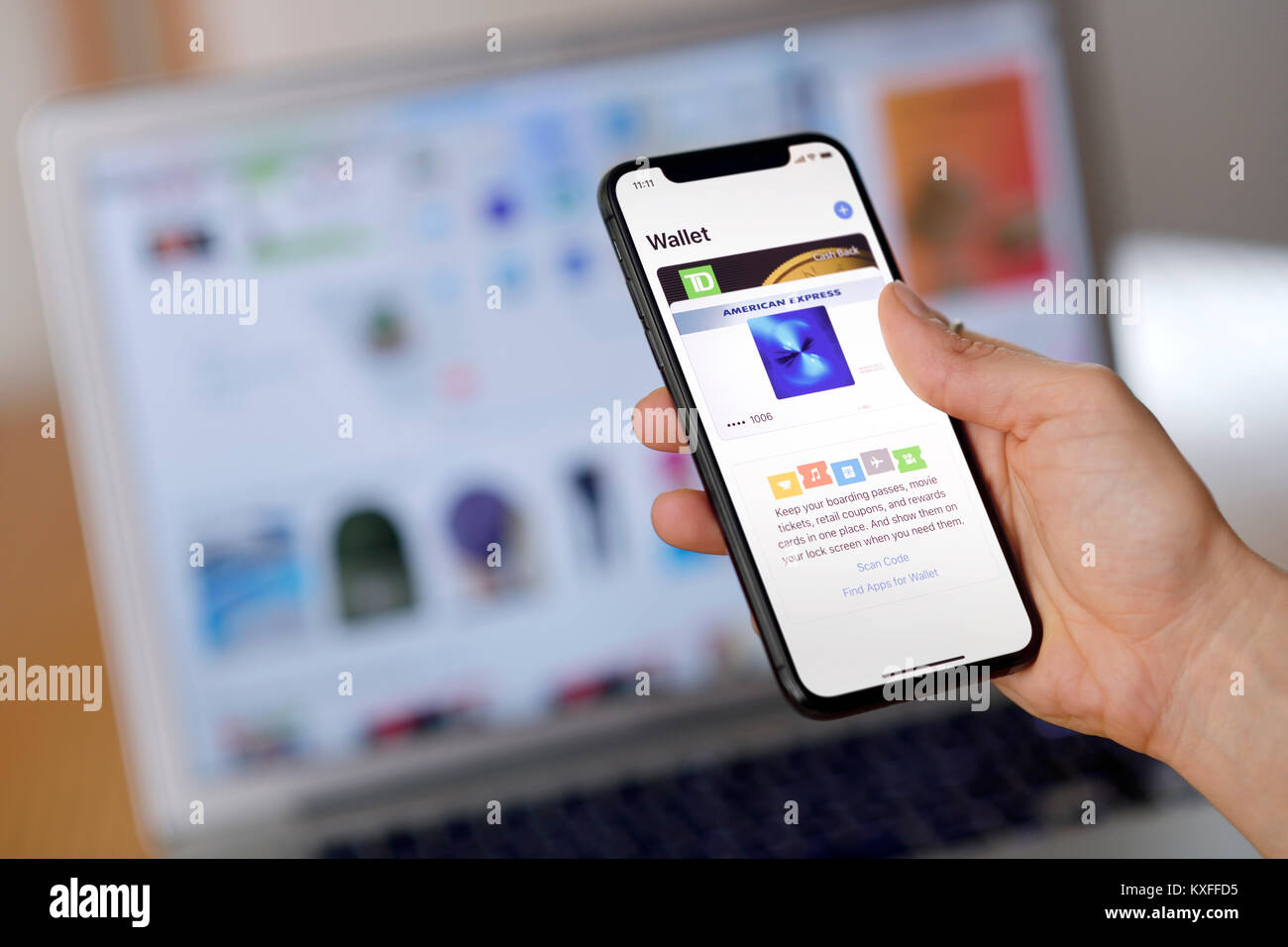 Nahaufnahme einer Frau mit iPhone X in ihrer Hand das Einrichten des Apple Portemonnaie, eine elektronische Zahlung app Stores Kreditkarten für Online shopping. Stockfoto