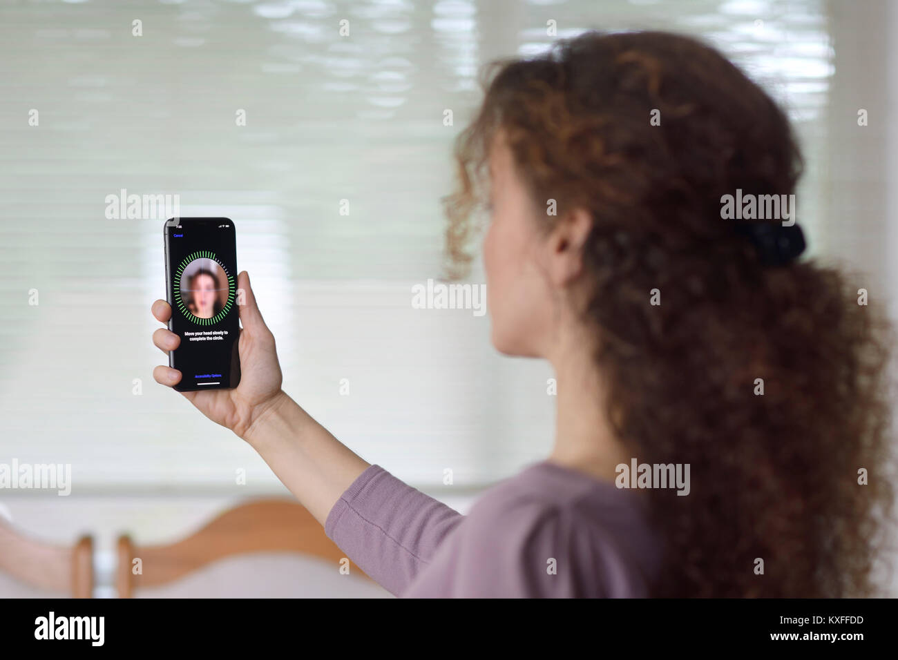 Junge Frau mit dem iPhone X einrichten Face ID, biometrische Authentifizierung, durch ihr Gesicht Scannen mit einer neuen Tiefe sensing Kamera Stockfoto