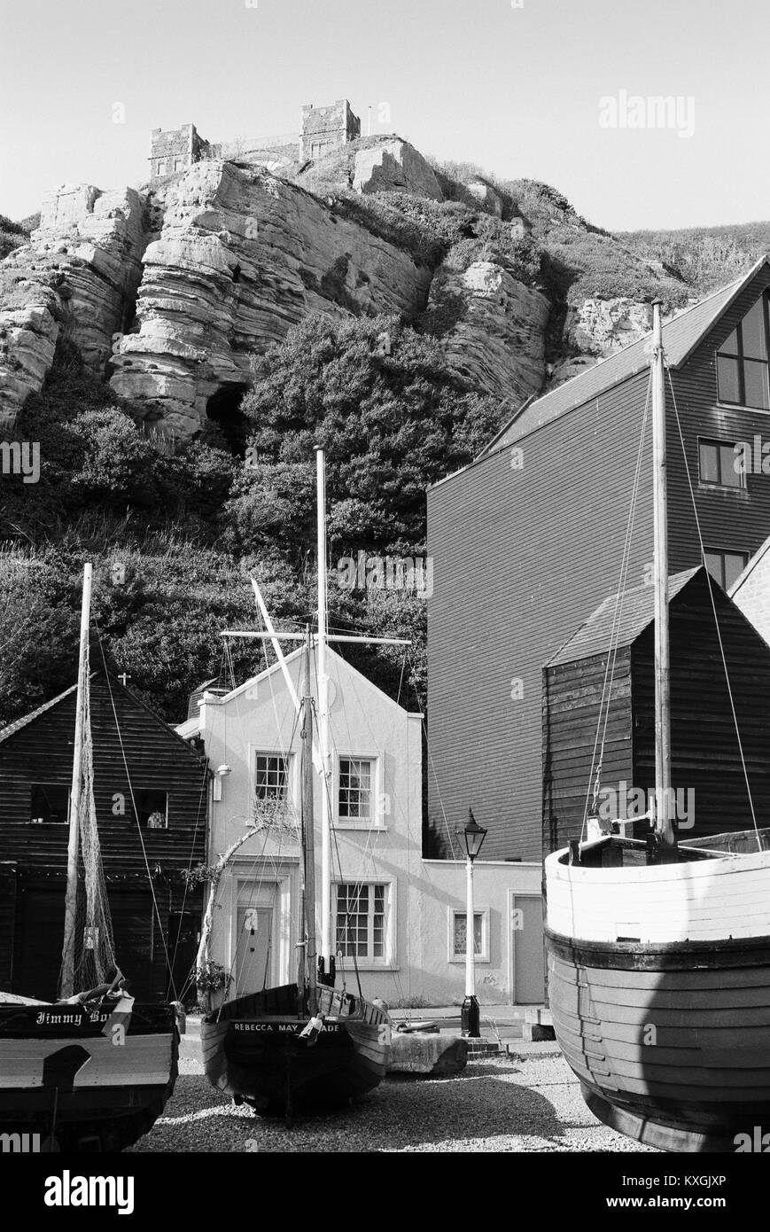 Net Hütten und Boote am Strand von Hastings, East Sussex, mit dem östlichen Hügel im Hintergrund Stockfoto