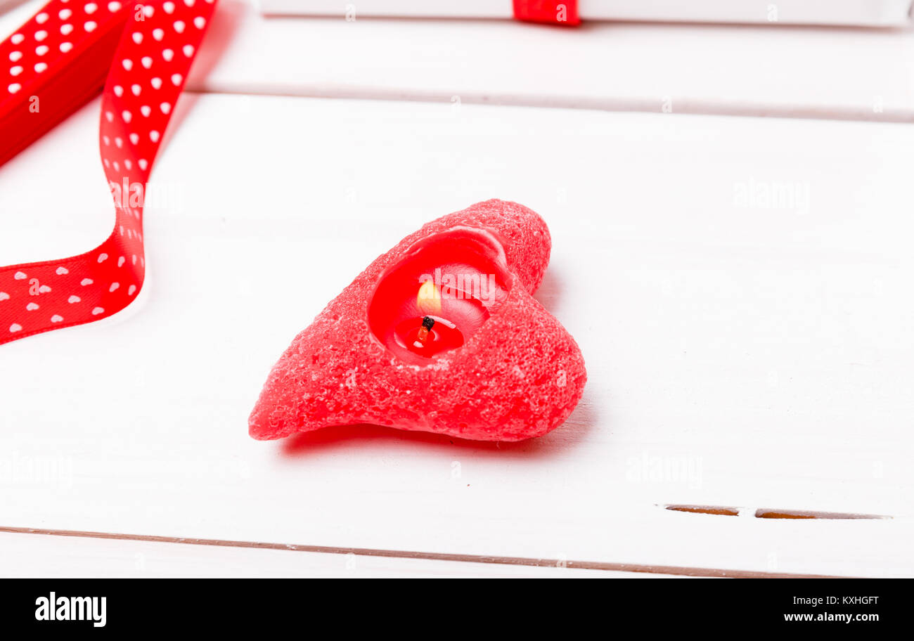 Kerze in Form roten Herzen auf weißem Hintergrund Holz, Red Ribbon. Valentinstag Konzept. Stockfoto