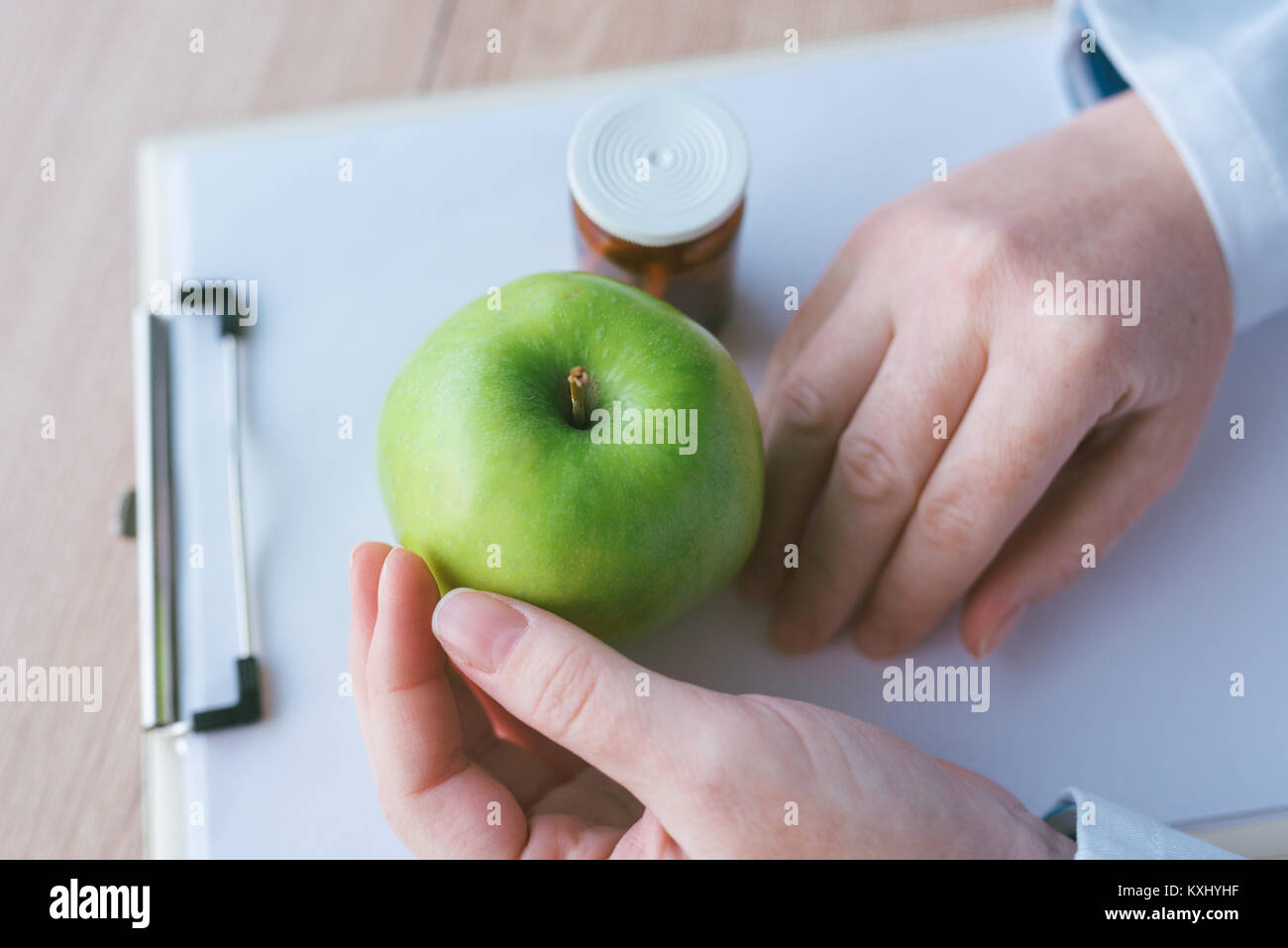 Arzt apple Beratung statt Pillen und Antibiotika, weibliche Hände im weißen Mantel mit grünen Früchte als vorteilhaften Weise zu erreichen und gesund l pflegen Stockfoto