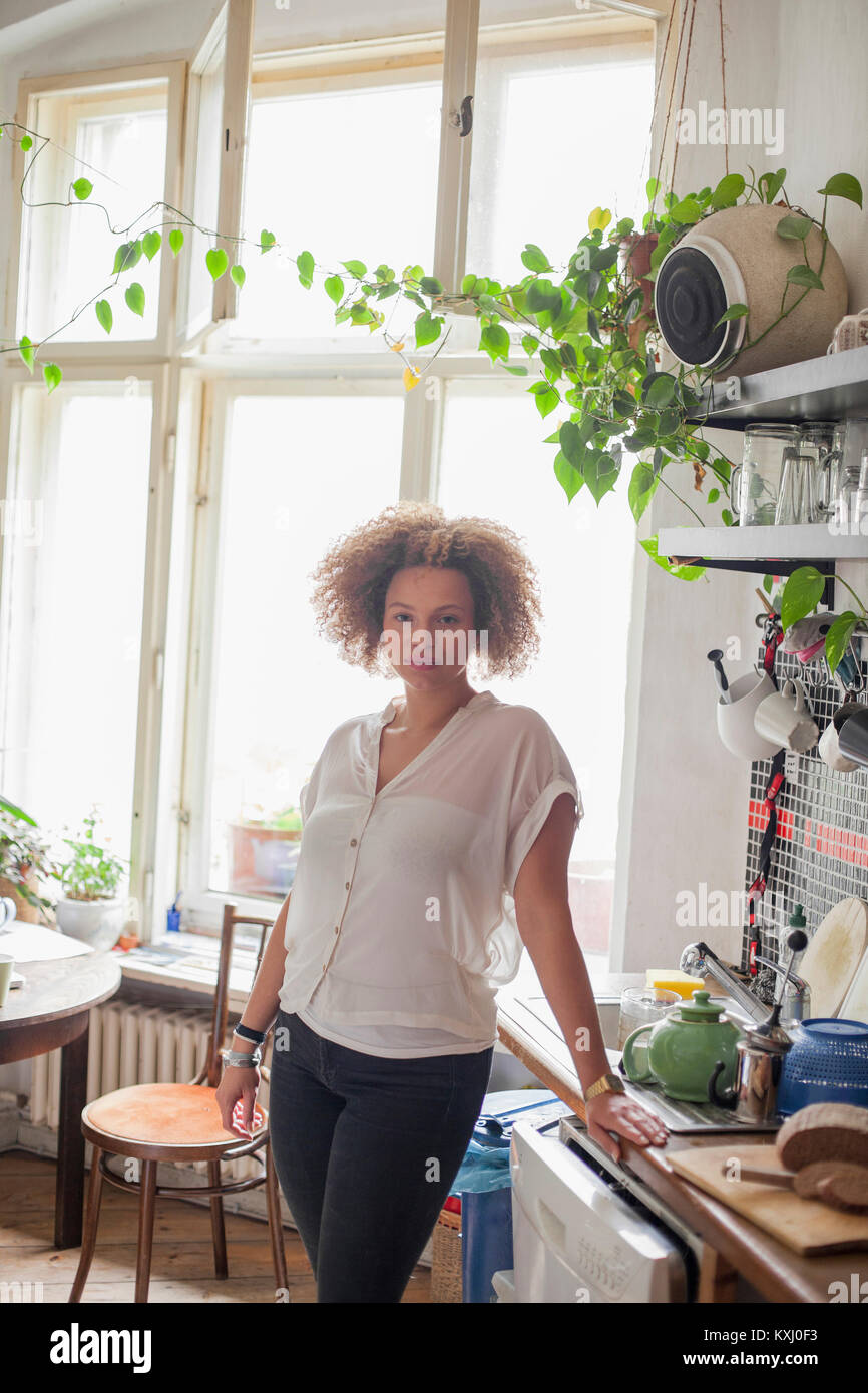 Porträt einer jungen Frau, die zu Hause an der Küchentreke am Fenster steht Stockfoto