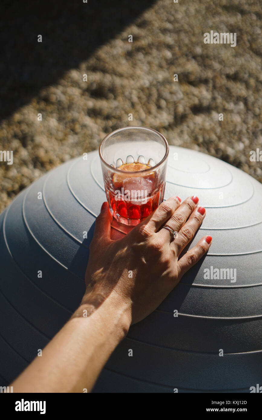 Verkürzte Hand einer Frau mit Getränk auf weißem Übungsball Stockfoto