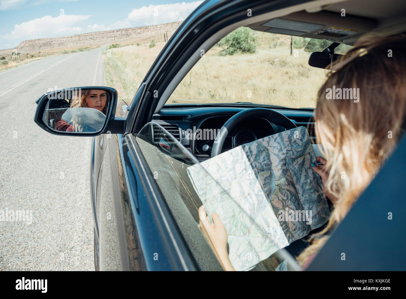Blick über die Schulter der Frau im Auto sitzen auf der Karte suchen Stockfoto