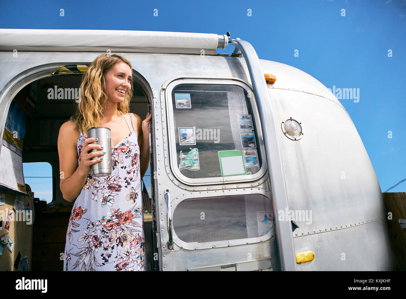 Junge Frau mit Kaffee aus der Suche von airstream Tür Stockfoto