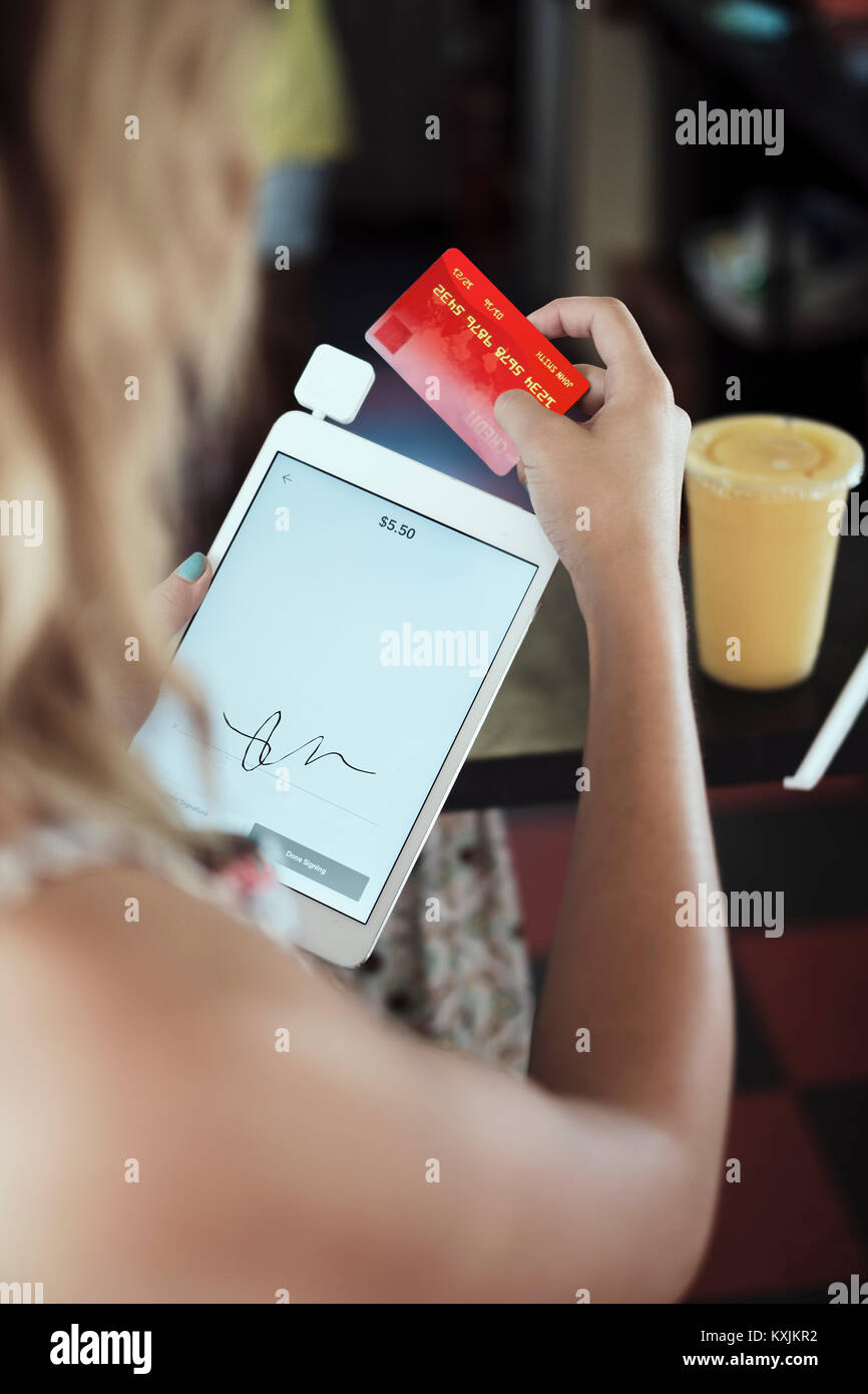 Blick über die Schulter der jungen Frau mit digitalen Tablet und Kreditkarte Stockfoto