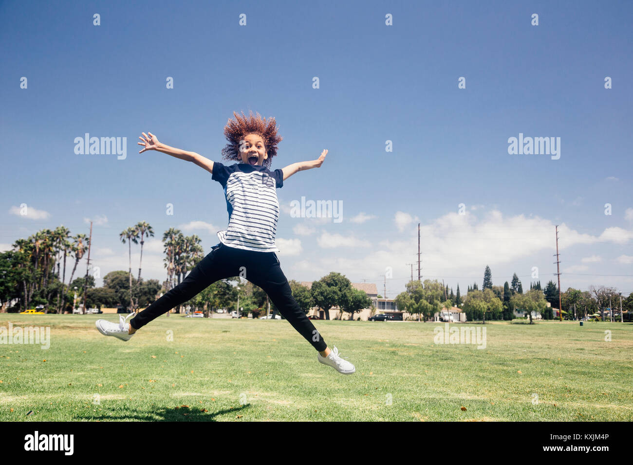 Schulmädchen tun star Jump auf Schule Sportplatz Stockfoto