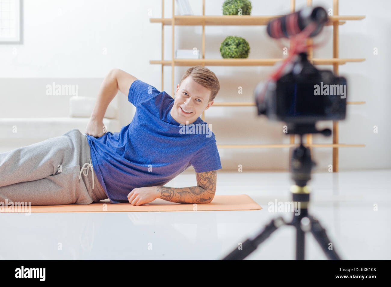 Fröhliche Blogger auf dem Boden und lächelt in die Kamera Stockfoto