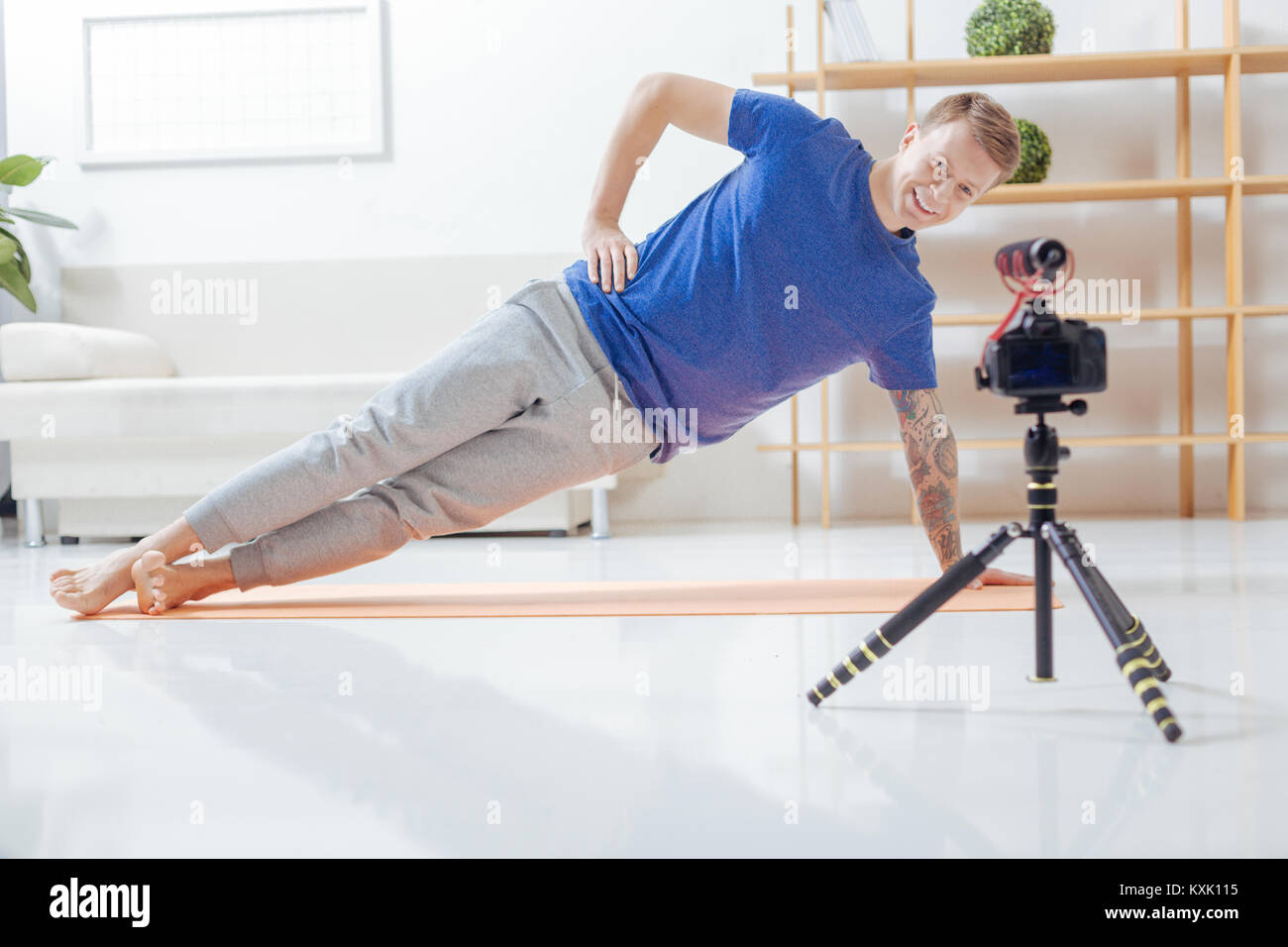 Lächelnde Trainer mit Blick auf die Kamera und die Übungen auf der Matte Stockfoto