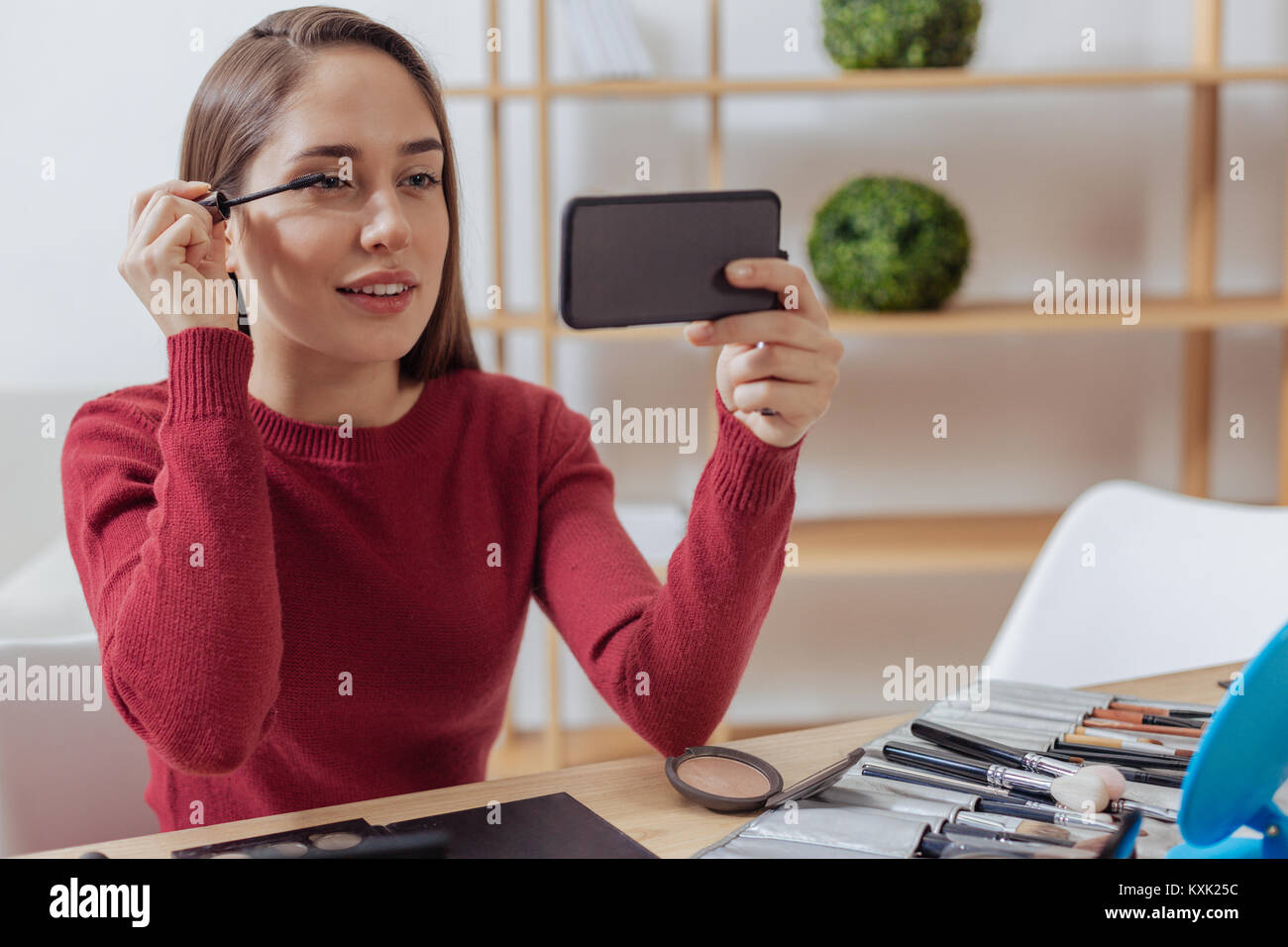 Ruhige Schönheit blogger setzen auf Wimperntusche und an Ihr Smartphone Stockfoto