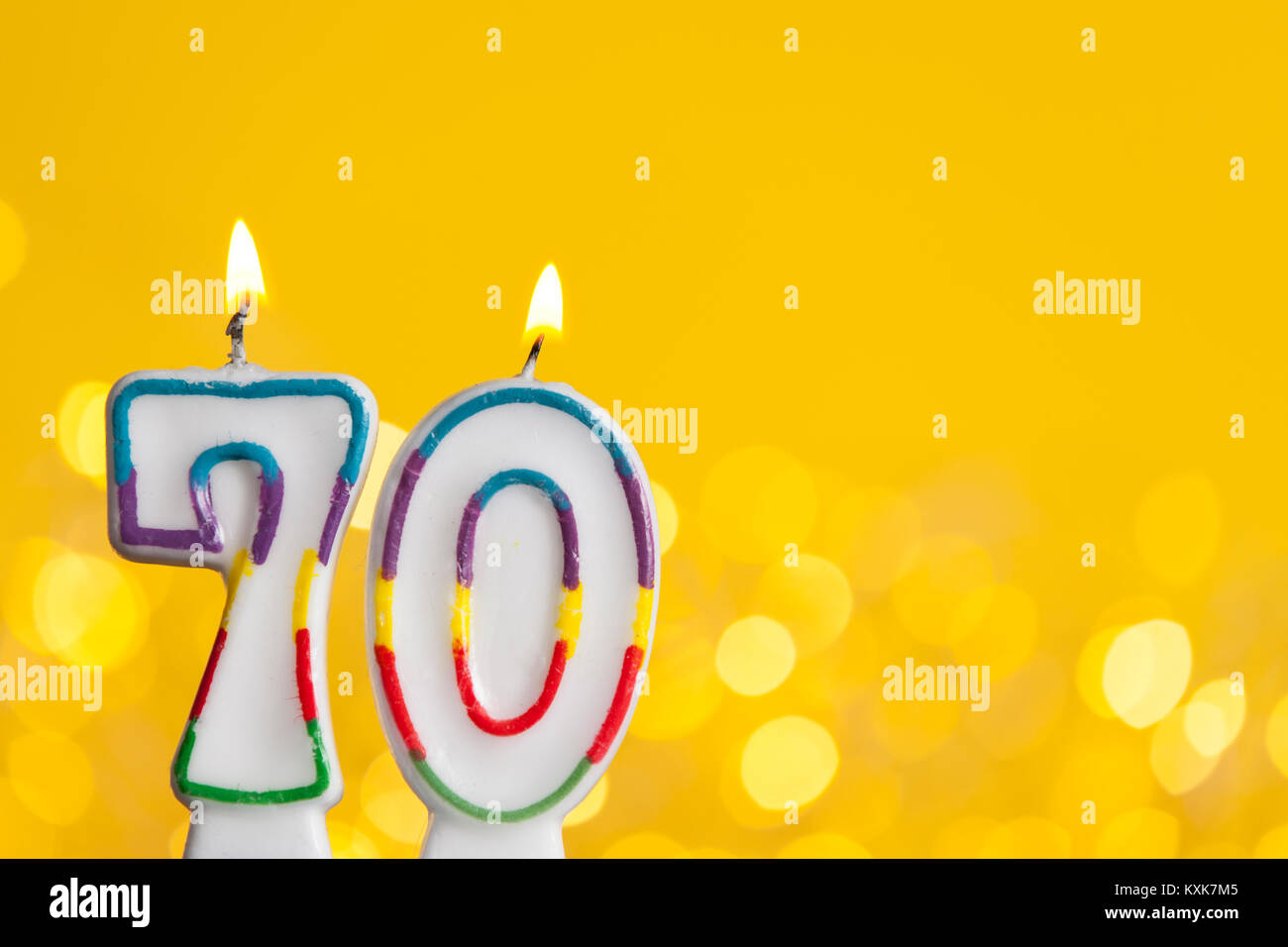 Nummer 70 Geburtstag Kerze gegen eine helle Lichter und gelbem Hintergrund Stockfotografie