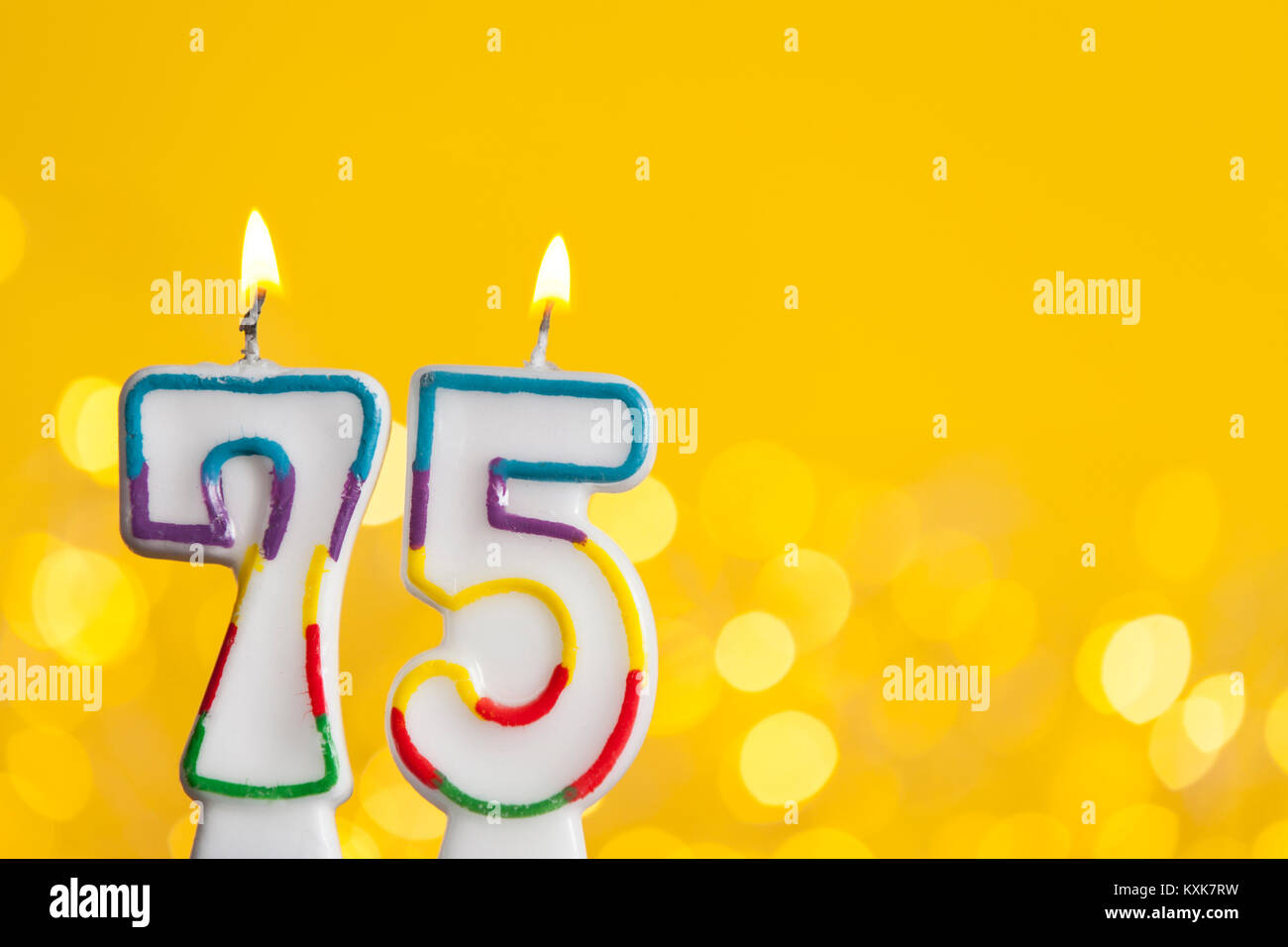 Nummer 75 Geburtstag Kerze gegen eine helle Lichter und gelbem