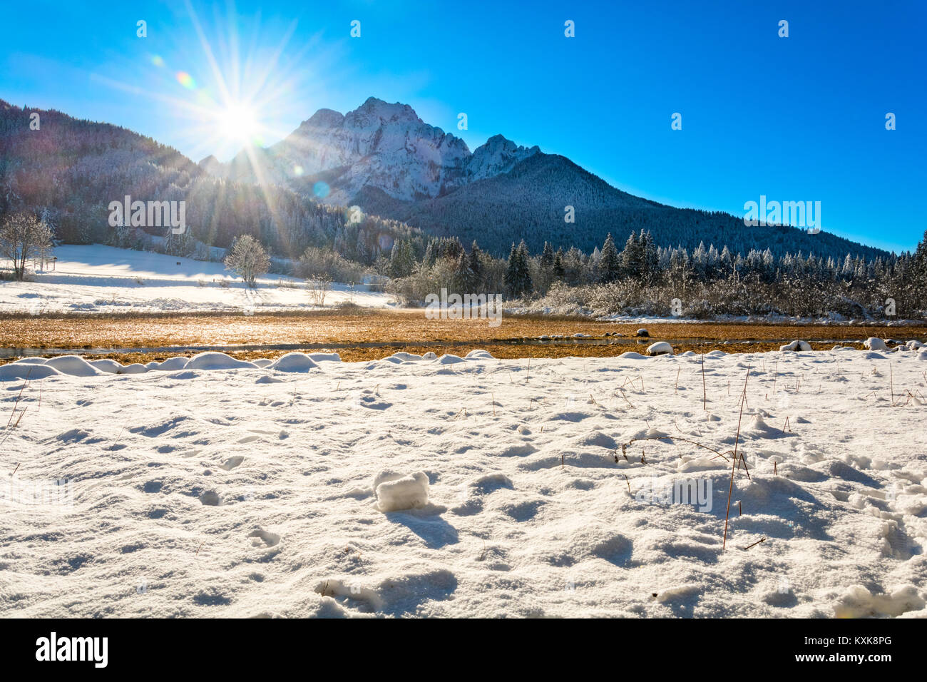Bereich der Schnee am Zelenci und die Sonne hinter den Bergen Stockfoto
